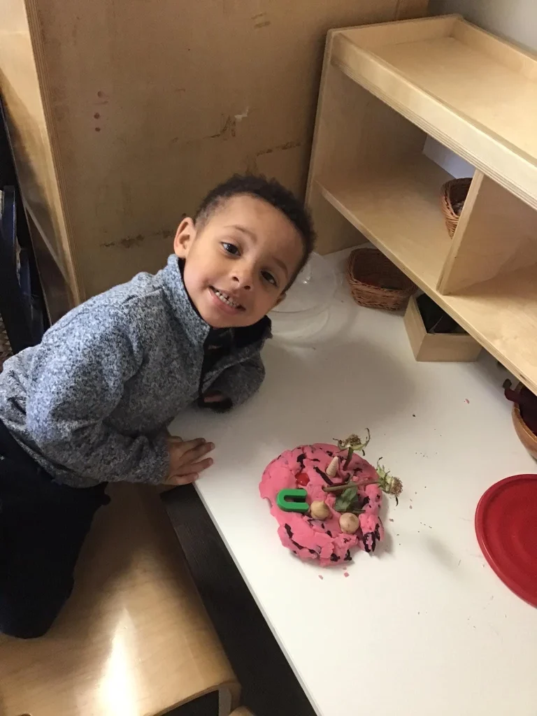 A child at Creative Garden Smile next to his art craft
