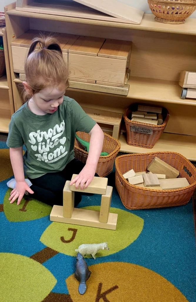 A child stacks blocks at creative garden