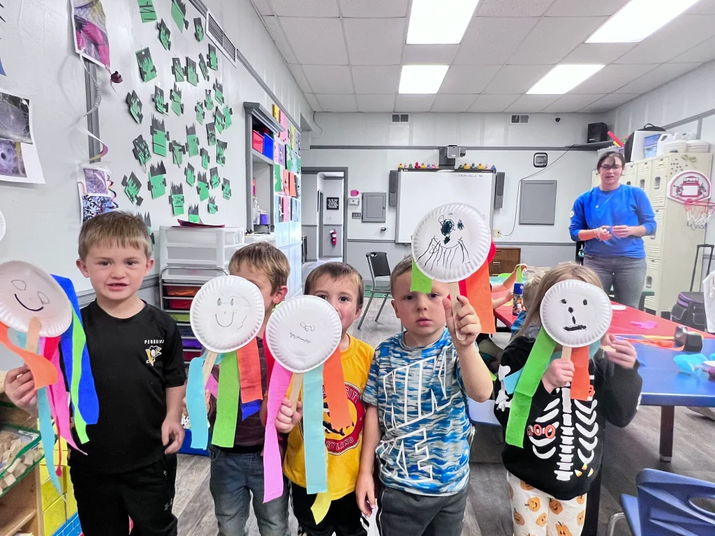 Children hold up faces that they've made with arts and crafts at Keystone SMILES CLC