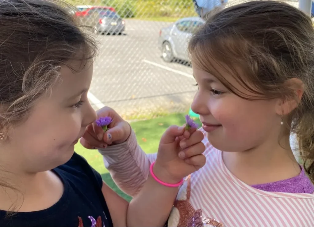 Children smell each others' flowers at Learning Tree