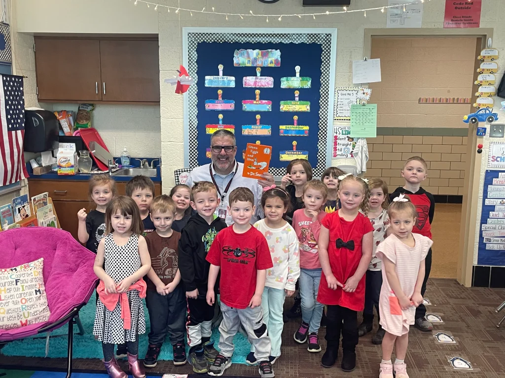 Children at Victory Elementary gather around a Staff Member.
